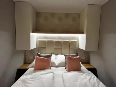 a bedroom with a bed with white sheets and pink pillows at Premium mobile home Eden in Velenje
