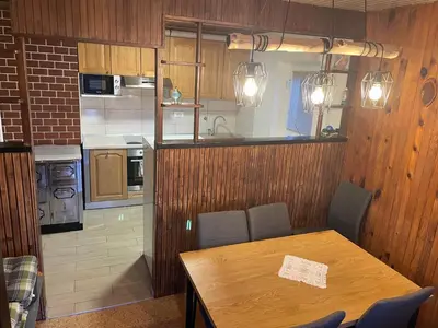 a kitchen with a wooden table with chairs and a dining room at Apartma Šohen in Kočevje