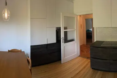 a kitchen with white cabinets and a wooden floor at Spacious Apartment - green & peaceful in Ljubljana
