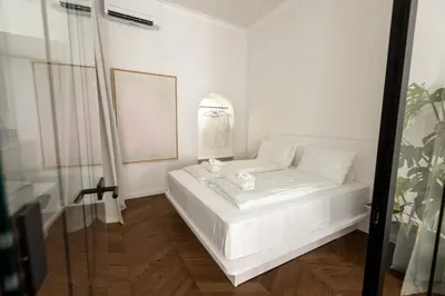 a white bedroom with a white bed and a mirror at Swanky Residence, 4 stars, city centre in Ljubljana