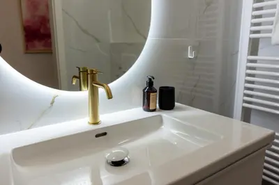 a bathroom sink with a gold faucet and a mirror at Swanky Residence, 4 stars, city centre in Ljubljana