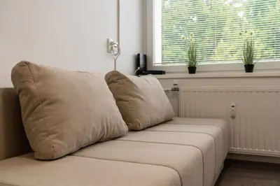 a couch sitting in a living room with two windows at Apartma Nadja in Maribor