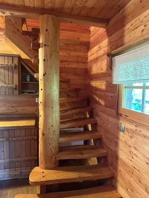 a wooden staircase in a log cabin with a window at Hiška ob potočku in Ljubno