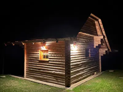 a log cabin with a window at night at Hiška ob potočku in Ljubno