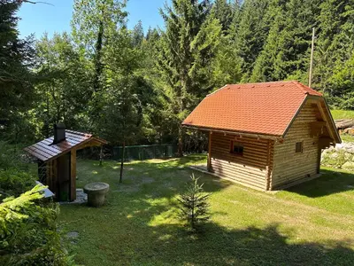 a small cabin with an orange roof in a yard at Hiška ob potočku in Ljubno