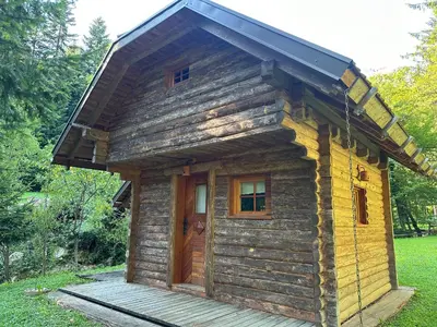 a small log cabin with a door on a deck at Hiška ob potočku in Ljubno