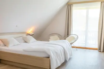 a bedroom with a white bed with two chairs and a window at Apartment Rosemary in Topolšica