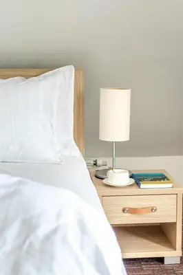a bed with a table with a lamp and a book at Apartment Rosemary in Topolšica