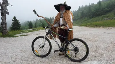 a man in a costume standing next to a bike at Chalet Zlatica Velika Planina in Stahovica