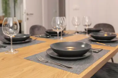 a wooden table with plates and wine glasses on it at Apartments Grahek in Ljubljana