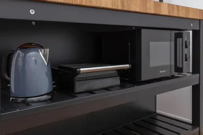 a tea kettle and books on a shelf in a microwave at Apartments Grahek in Ljubljana