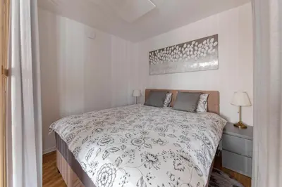 a white bedroom with a bed and a picture on the wall at Apartments Grahek in Ljubljana