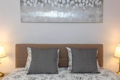 a bed with two pillows and a painting above it at Apartments Grahek in Ljubljana