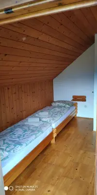 a bed in a room with a wooden ceiling at Holiday House Jezerka in Bohinj