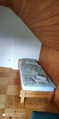 a bed in a room with a wooden ceiling at Holiday House Jezerka in Bohinj