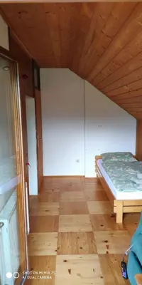 a bedroom with a bed and a wooden floor at Holiday House Jezerka in Bohinj