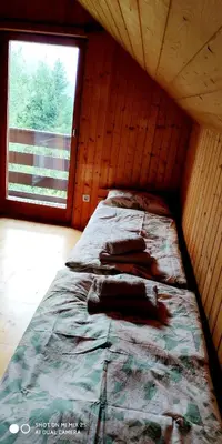 a bed in a wooden room with a window at Holiday House Jezerka in Bohinj