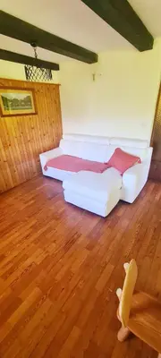 a white couch in a room with a wooden floor at Holiday House Jezerka in Bohinj