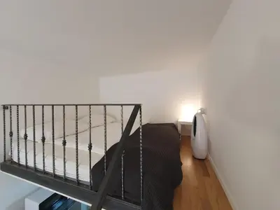 a small bedroom with a bed and a staircase at Chic studios Wendy in centre Tour As Ljubljana in Ljubljana