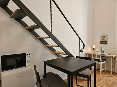a dining room with a black table and a staircase at Chic studios Wendy in centre Tour As Ljubljana in Ljubljana