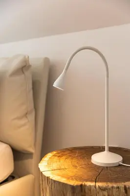 a white lamp on a wooden table next to a bed at EROS APARTMENT Kranjska Gora in Kranjska Gora