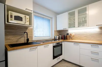 a kitchen with white cabinets and a sink and a microwave at Aparthouse Jana Breg in Žirovnica
