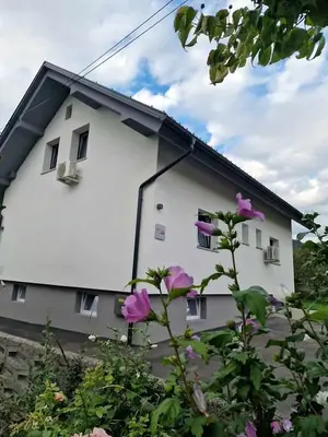 a white house with purple flowers in front of it at Aparthouse Jana Breg in Žirovnica