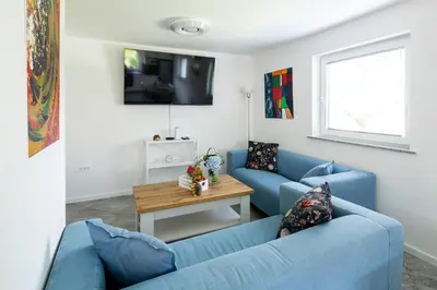 a living room with two blue couches and a table at Aparthouse Jana Breg in Žirovnica