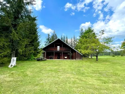 a large wooden barn in a field with trees at Cabin in Nature in Nova Vas
