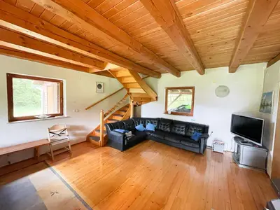 a living room with a black couch and a wooden ceiling at Cabin in Nature in Nova Vas