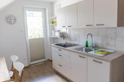 a kitchen with white cabinets and a sink at Apartments Olip in Bled