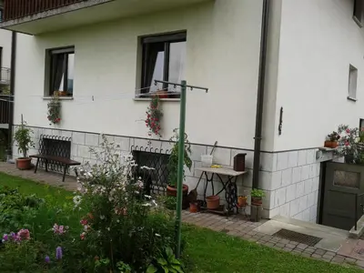 a garden in front of a white house with flowers at Apartments Boris in Bled