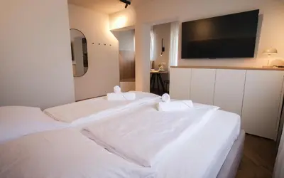 two white beds in a room with a flat screen tv at M16 Apartments in Ljubljana