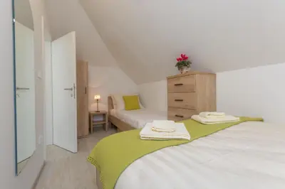 a white bedroom with two beds and a dresser at Old Town first floor in Ljubljana