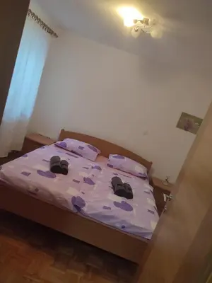 a bedroom with a bed with purple sheets and shoes on it at Počitniško stanovanje Aurora in Bovec