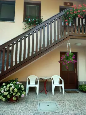 a patio with two chairs and a table under a staircase at Počitniško stanovanje Aurora in Bovec