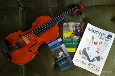 a violin and a book next to a magazine at Cherry house - cosy house - ideal for bear watching, in the neighborhood of the medieval Snežnik castle in Stari Trg pri Ložu