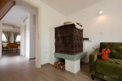 a fireplace in a living room with a green couch at Cherry house - cosy house - ideal for bear watching, in the neighborhood of the medieval Snežnik castle in Stari Trg pri Ložu