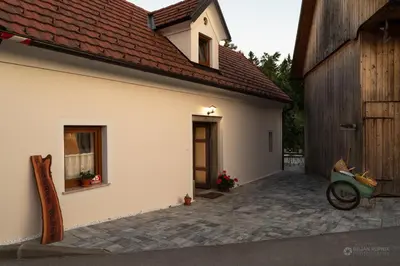 a white house with a window and a building at Cherry house - cosy house - ideal for bear watching, in the neighborhood of the medieval Snežnik castle in Stari Trg pri Ložu