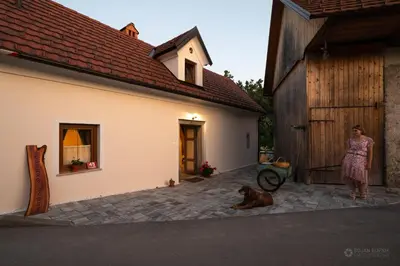 a woman and a dog standing next to a building at Cherry house - cosy house - ideal for bear watching, in the neighborhood of the medieval Snežnik castle in Stari Trg pri Ložu