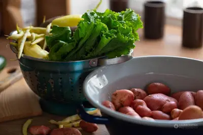 a bowl of potatoes and greens next to a bowl of vegetables at Cherry house - cosy house - ideal for bear watching, in the neighborhood of the medieval Snežnik castle in Stari Trg pri Ložu