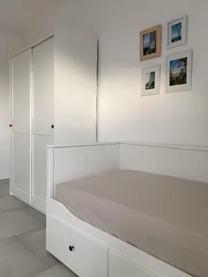 a white bedroom with white cabinets and a bed at The View 22 in Cerklje na Gorenjskem