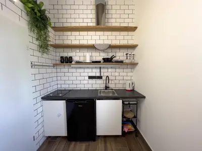 a kitchen with a black counter and white brick wall at Riverside studio 1 in Ljubljana