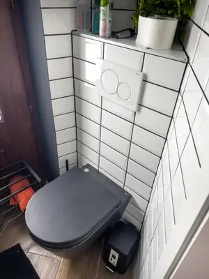a bathroom with a toilet in a white tiled wall at Riverside studio 1 in Ljubljana