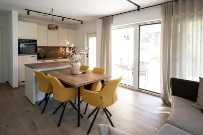 a kitchen and dining room with a wooden table and chairs at Apartments Kras 24 with Pool in Sežana