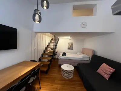a living room with a couch and a stair case at Ljubljana Studios in Ljubljana