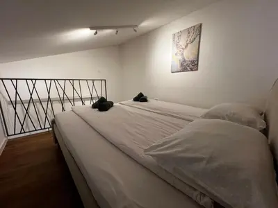 a white bed with two black cats sitting on it at Ljubljana Studios in Ljubljana