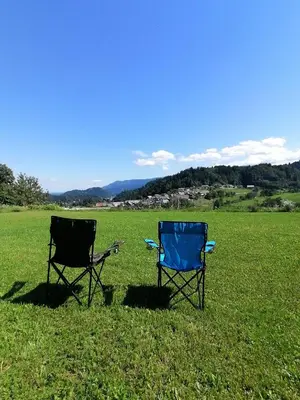 two chairs sitting in the grass in a field at Apartments at Klemen in Zgornje Gorje