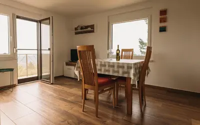 a dining room with a table and chairs and two windows at Apartma Hiša na Ravnah with hot tub in Pišece