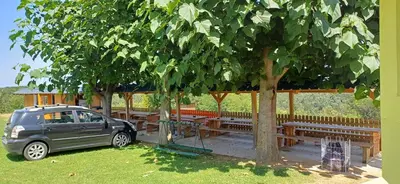 a car parked under a tree next to wooden benches at Hisa jager in Gradišče v Slovenskih Goricah